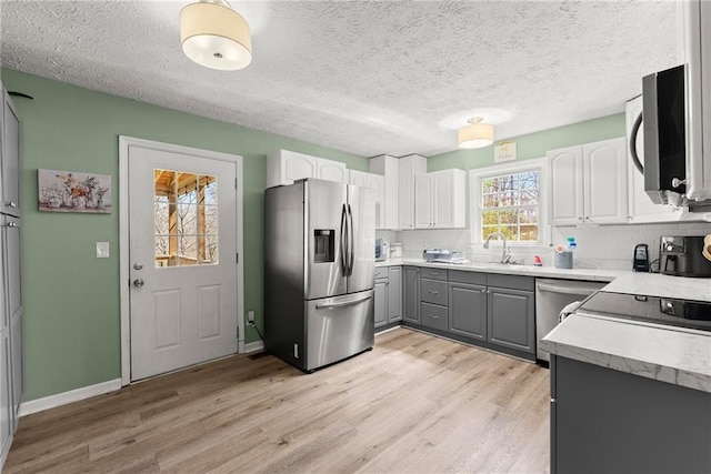 165 Grant Ford Dr, Dawsonville, GA 30534 - kitchen featuring stainless steel appliances, gray cabinets, light wood finished floors, decorative backsplash, and white cabinetry
