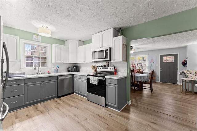 165 Grant Ford Dr, Dawsonville, GA 30534 - kitchen featuring appliances with stainless steel finishes, gray cabinets, a textured ceiling, decorative backsplash, and plenty of natural light