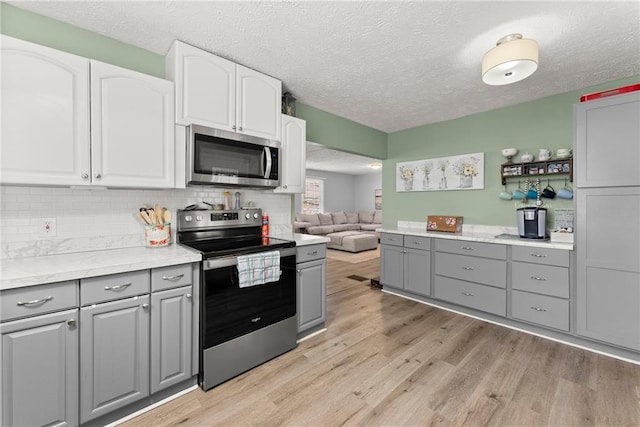 165 Grant Ford Dr, Dawsonville, GA 30534 - kitchen featuring gray cabinets, appliances with stainless steel finishes, light wood finished floors, a textured ceiling, and decorative backsplash