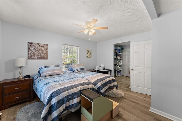 165 Grant Ford Dr, Dawsonville, GA 30534 - bedroom featuring light wood-style flooring, a textured ceiling, ceiling fan, a closet, and a walk in closet