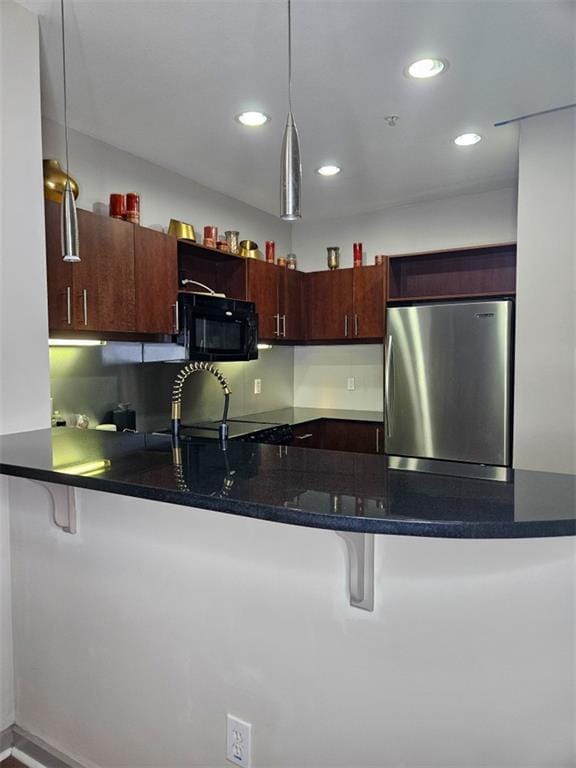 390 17th St NW Unit 2025, Atlanta, GA 30363 - kitchen with freestanding refrigerator, black microwave, a breakfast bar, a peninsula, and decorative light fixtures