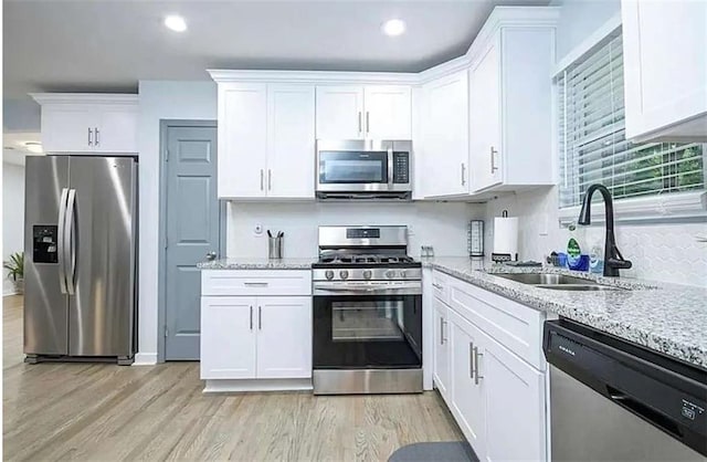 kitchen featuring white cabinetry, appliances with stainless steel finishes, light stone counters, and a sink