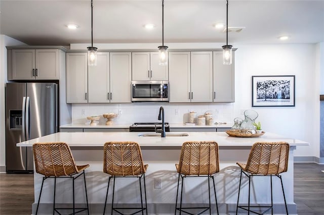 kitchen featuring decorative light fixtures, stainless steel appliances, gray cabinets, and sink