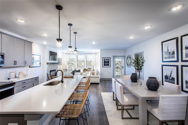 kitchen featuring an island with sink, hanging light fixtures, gray cabinetry, and sink