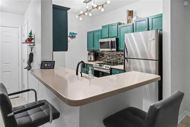 kitchen featuring appliances with stainless steel finishes, kitchen peninsula, a kitchen bar, and tasteful backsplash