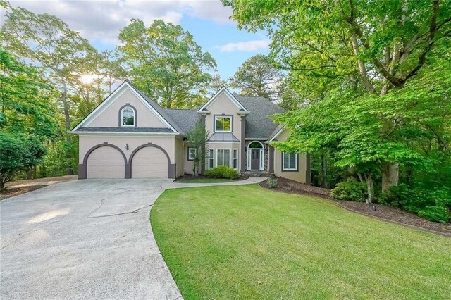 view of front of house featuring a front lawn, stucco siding, and driveway
