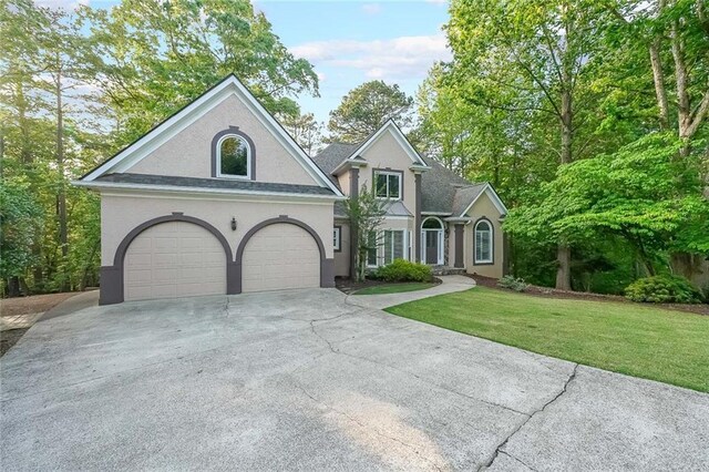 view of front of property featuring a garage, stucco siding, a front yard, and concrete driveway