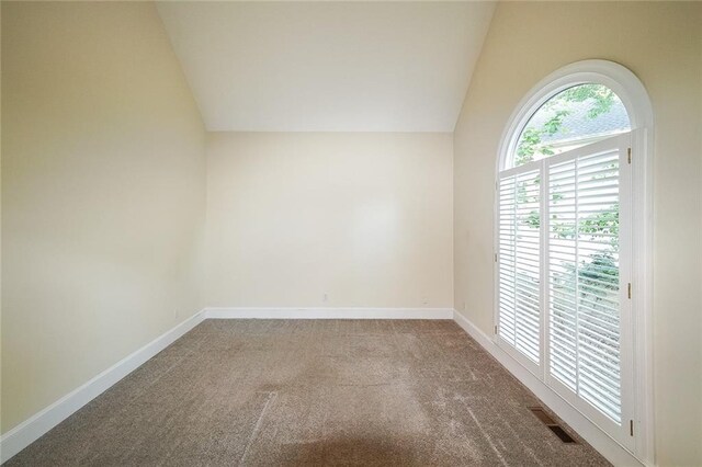unfurnished room with carpet floors, baseboards, visible vents, and lofted ceiling