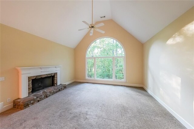unfurnished living room featuring ceiling fan, a stone fireplace, vaulted ceiling, carpet floors, and baseboards