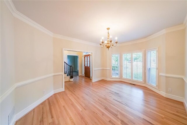 unfurnished dining area featuring an inviting chandelier, crown molding, light wood finished floors, and stairs