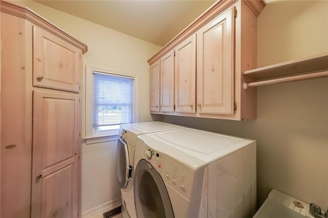 clothes washing area with cabinet space, baseboards, and washing machine and dryer
