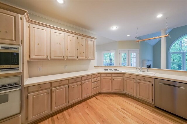 kitchen with appliances with stainless steel finishes, a sink, light brown cabinets, light countertops, and light wood-type flooring