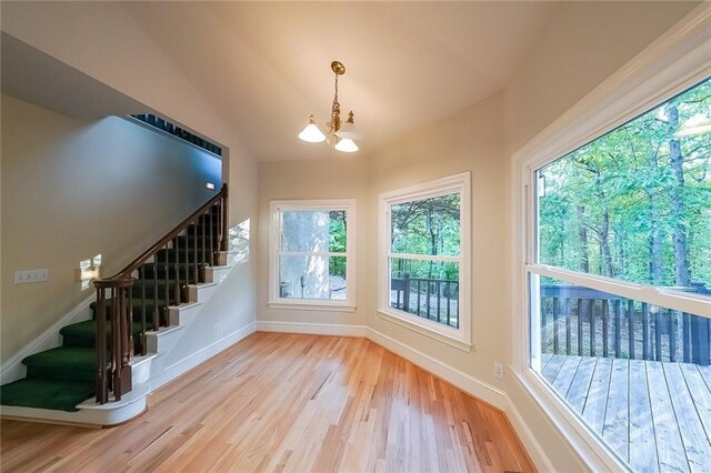 doorway with stairway, plenty of natural light, light wood finished floors, and a chandelier