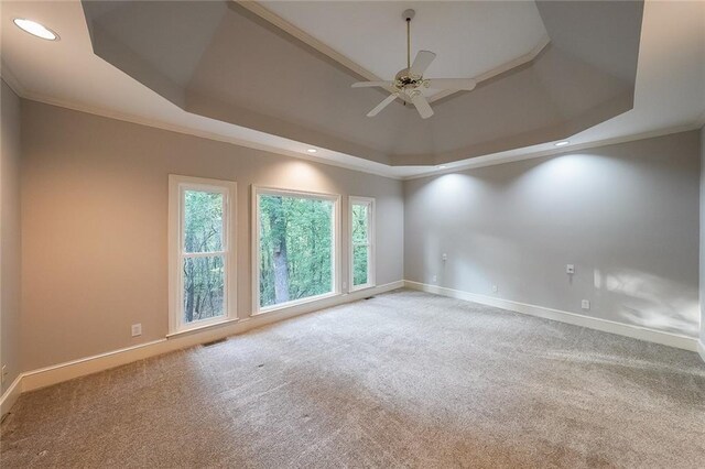carpeted spare room featuring crown molding, visible vents, baseboards, ceiling fan, and a raised ceiling