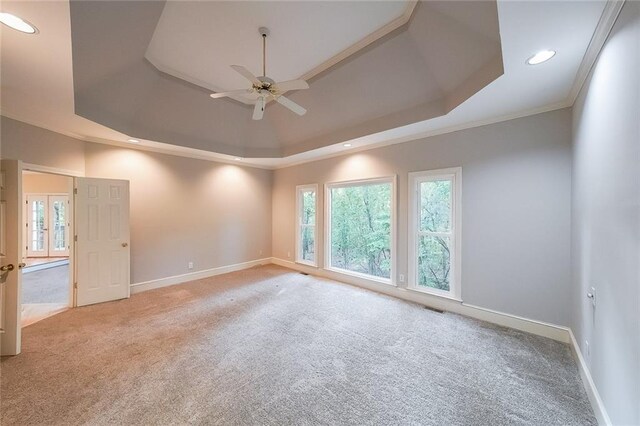 spare room featuring ceiling fan, carpet, baseboards, a tray ceiling, and visible vents