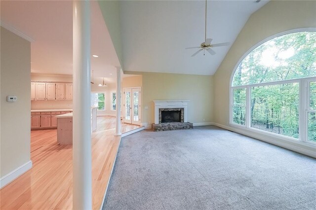unfurnished living room featuring ceiling fan, baseboards, high vaulted ceiling, and a fireplace