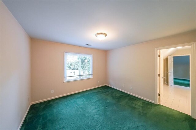 empty room with carpet floors, baseboards, and visible vents