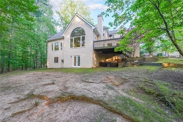 back of property with a wooden deck, a chimney, and stucco siding