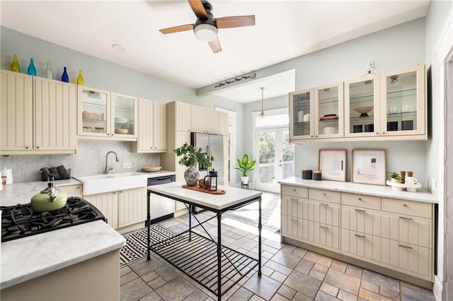 kitchen with sink, black appliances, pendant lighting, cream cabinetry, and backsplash