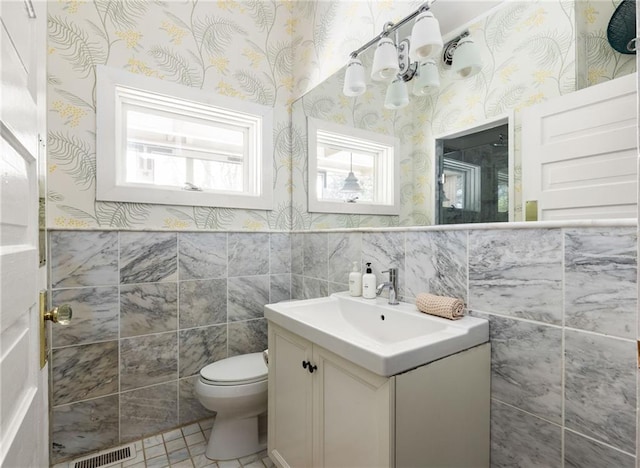 bathroom featuring tile patterned floors, vanity, toilet, and tile walls