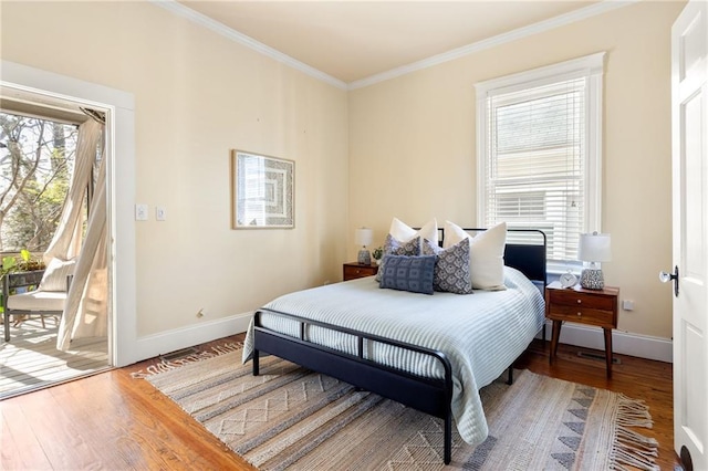 bedroom with multiple windows, hardwood / wood-style flooring, access to outside, and ornamental molding