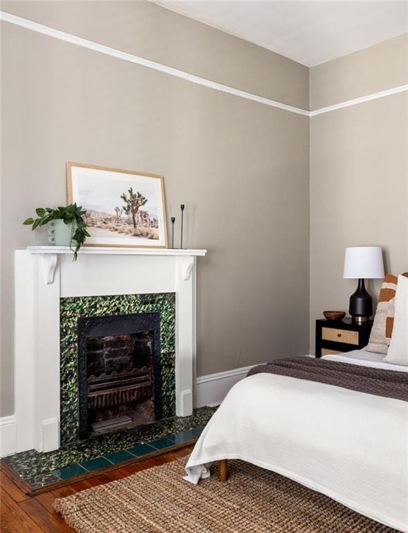 bedroom featuring a tiled fireplace and hardwood / wood-style flooring