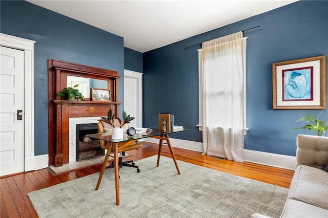 office area with wood-type flooring and a brick fireplace