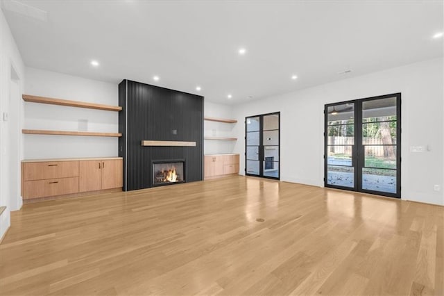 unfurnished living room with recessed lighting, french doors, light wood finished floors, and a fireplace