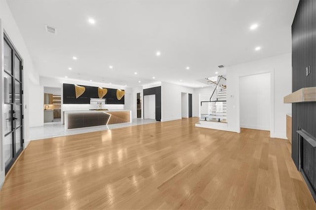 unfurnished living room featuring light wood-type flooring, visible vents, a large fireplace, and recessed lighting