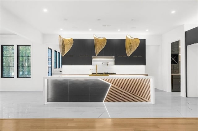 unfurnished living room featuring a sink, a large fireplace, light wood finished floors, and recessed lighting