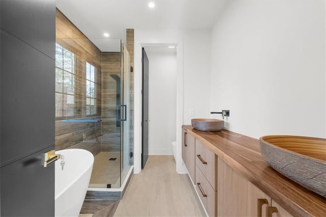 full bathroom with a shower stall, a sink, a soaking tub, baseboards, and recessed lighting