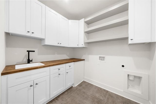 clothes washing area featuring hookup for a washing machine, a sink, hookup for an electric dryer, cabinet space, and baseboards