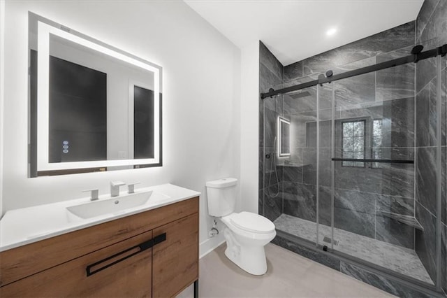 bathroom with baseboards, toilet, vanity, and a stall shower