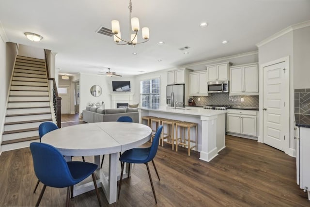 dining space featuring dark hardwood / wood-style flooring, ceiling fan with notable chandelier, and ornamental molding