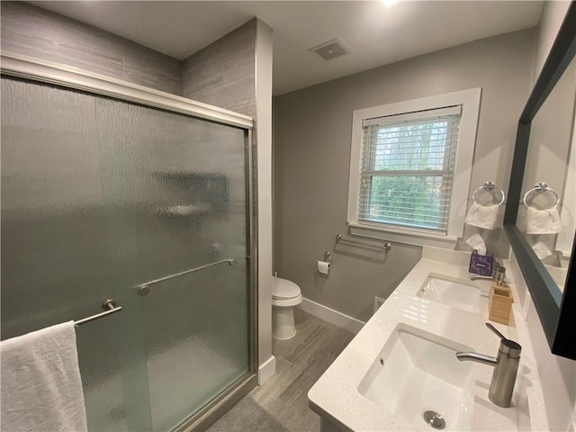 bathroom featuring vanity, hardwood / wood-style flooring, a shower with door, and toilet