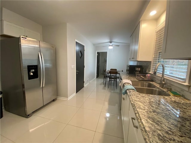 kitchen featuring light tile patterned flooring, sink, white cabinetry, stainless steel fridge, and light stone countertops