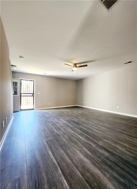 unfurnished room featuring ceiling fan, visible vents, baseboards, and dark wood-style floors