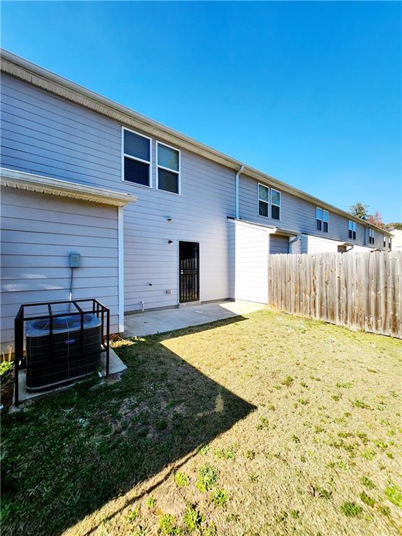 back of house with central air condition unit, a yard, a patio area, and fence