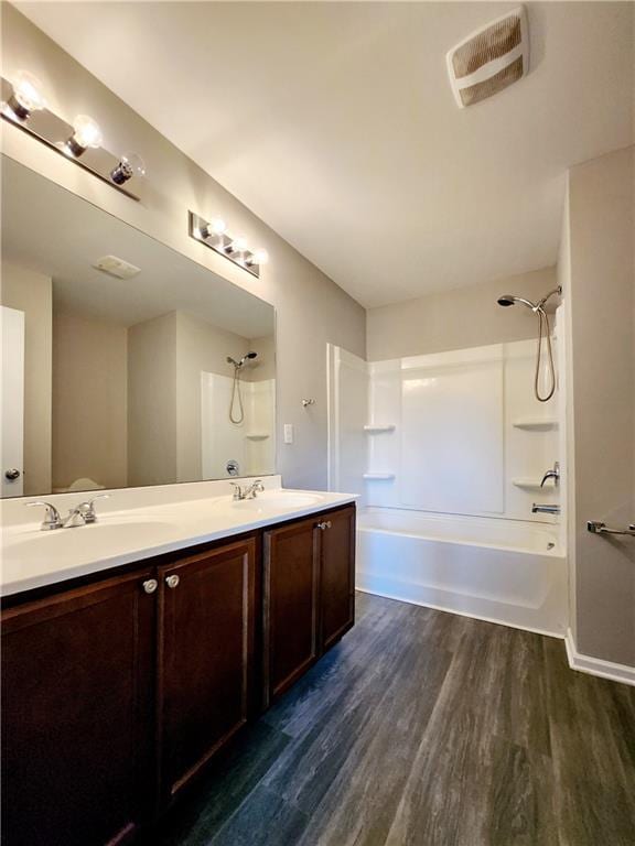 bathroom featuring a sink, wood finished floors, bathtub / shower combination, and double vanity