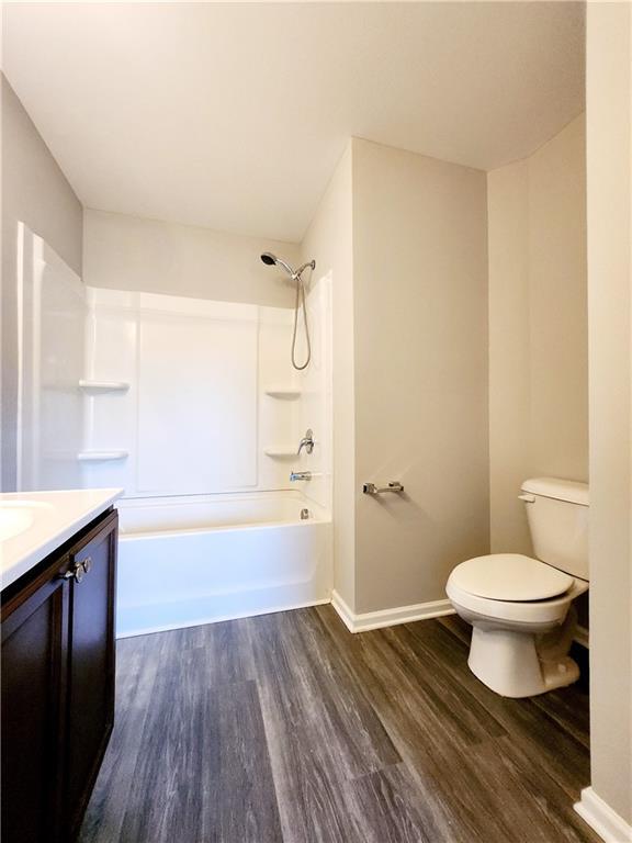 full bathroom featuring baseboards, toilet, shower / tub combination, wood finished floors, and vanity