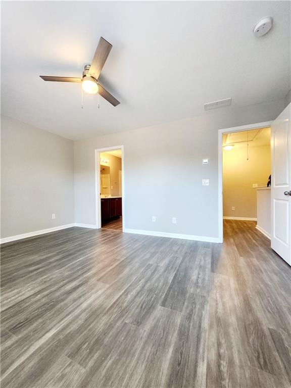 spare room with attic access, wood finished floors, and baseboards