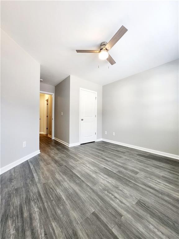 empty room with baseboards, dark wood-style flooring, and ceiling fan