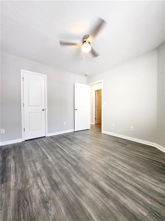 empty room with a ceiling fan, baseboards, and dark wood-style flooring