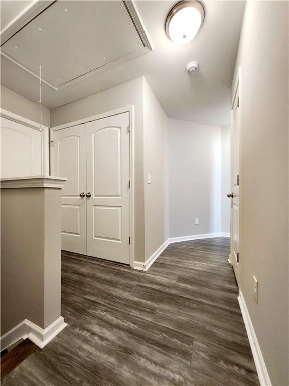 corridor featuring dark wood finished floors, attic access, and baseboards