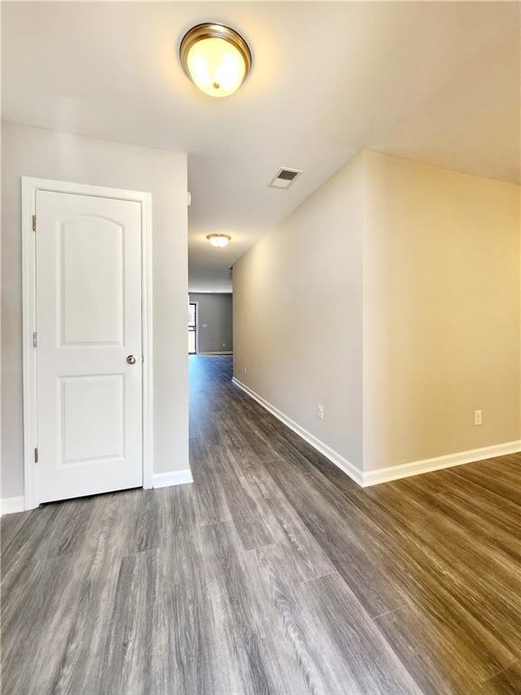 spare room with visible vents, dark wood-type flooring, and baseboards