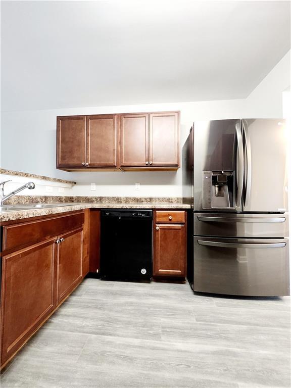 kitchen with a sink, light wood-style floors, black dishwasher, and stainless steel fridge with ice dispenser