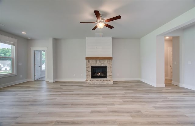 unfurnished living room featuring ceiling fan, light wood-type flooring, and a fireplace