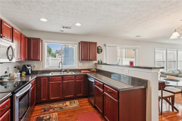 3698 Roseman Lndg, Cumming, GA 30040 - kitchen featuring a sink, stainless steel appliances, dark brown cabinets, dark wood-style floors, and dark countertops