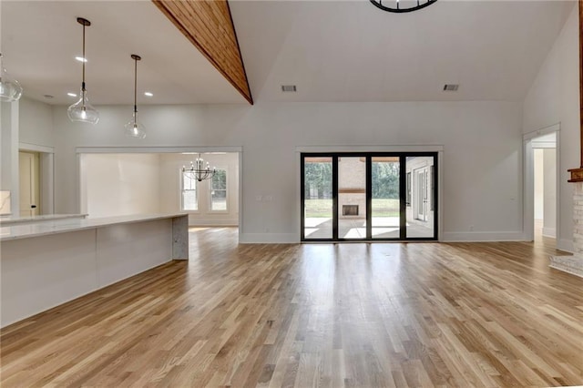 unfurnished living room with high vaulted ceiling, light hardwood / wood-style floors, and a healthy amount of sunlight