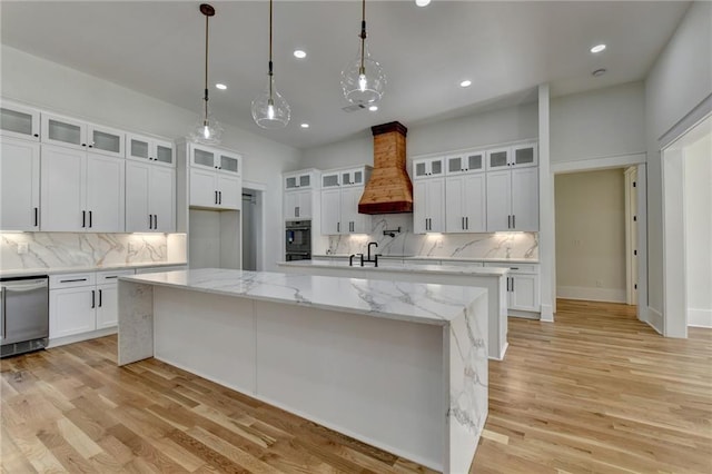 kitchen with premium range hood, white cabinetry, a large island with sink, dishwasher, and pendant lighting